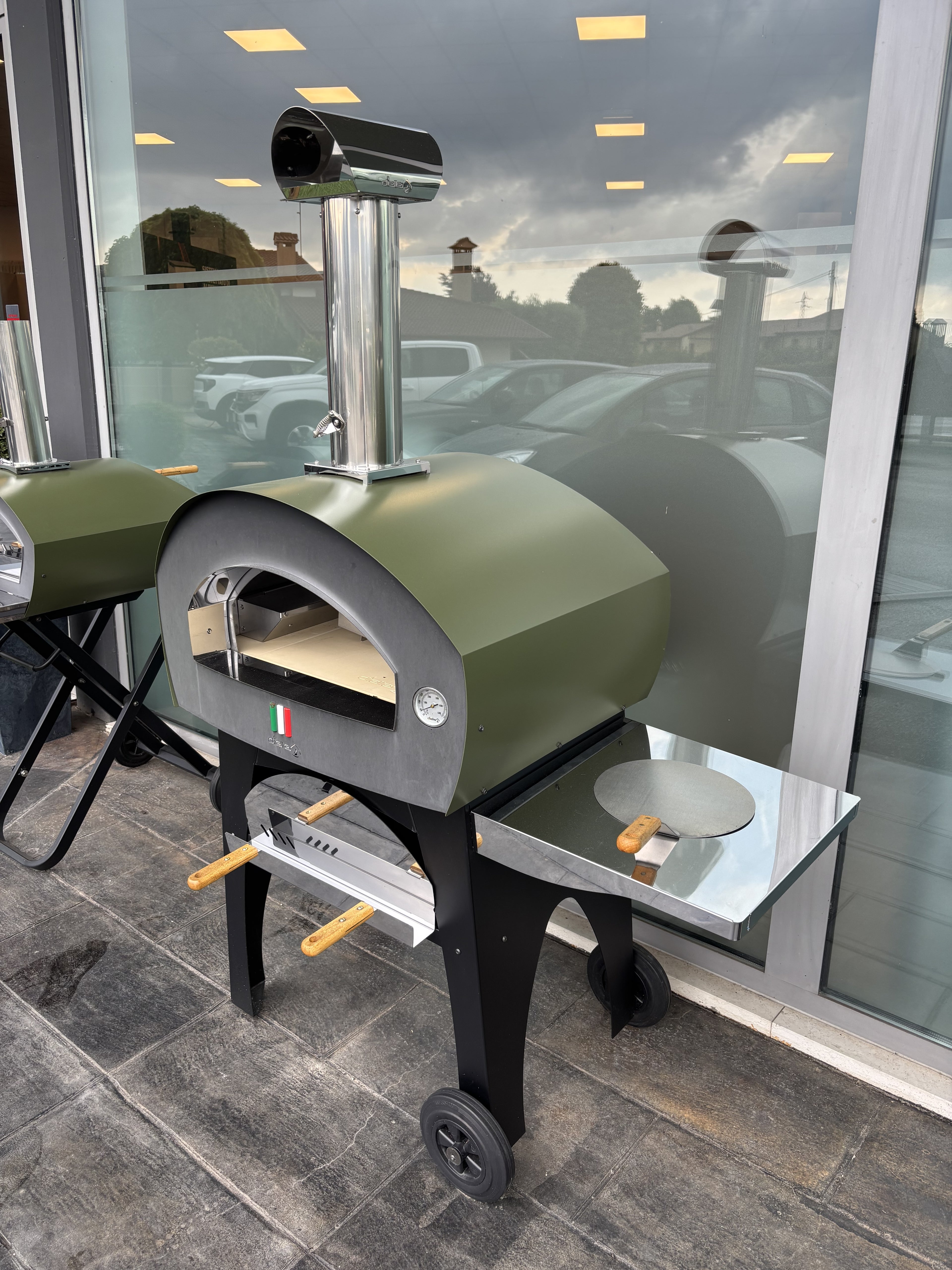 Forno a legna e gas Patio di Dielle Stufe con struttura in metallo e porta in vetro, ideale per cottura all'aperto.