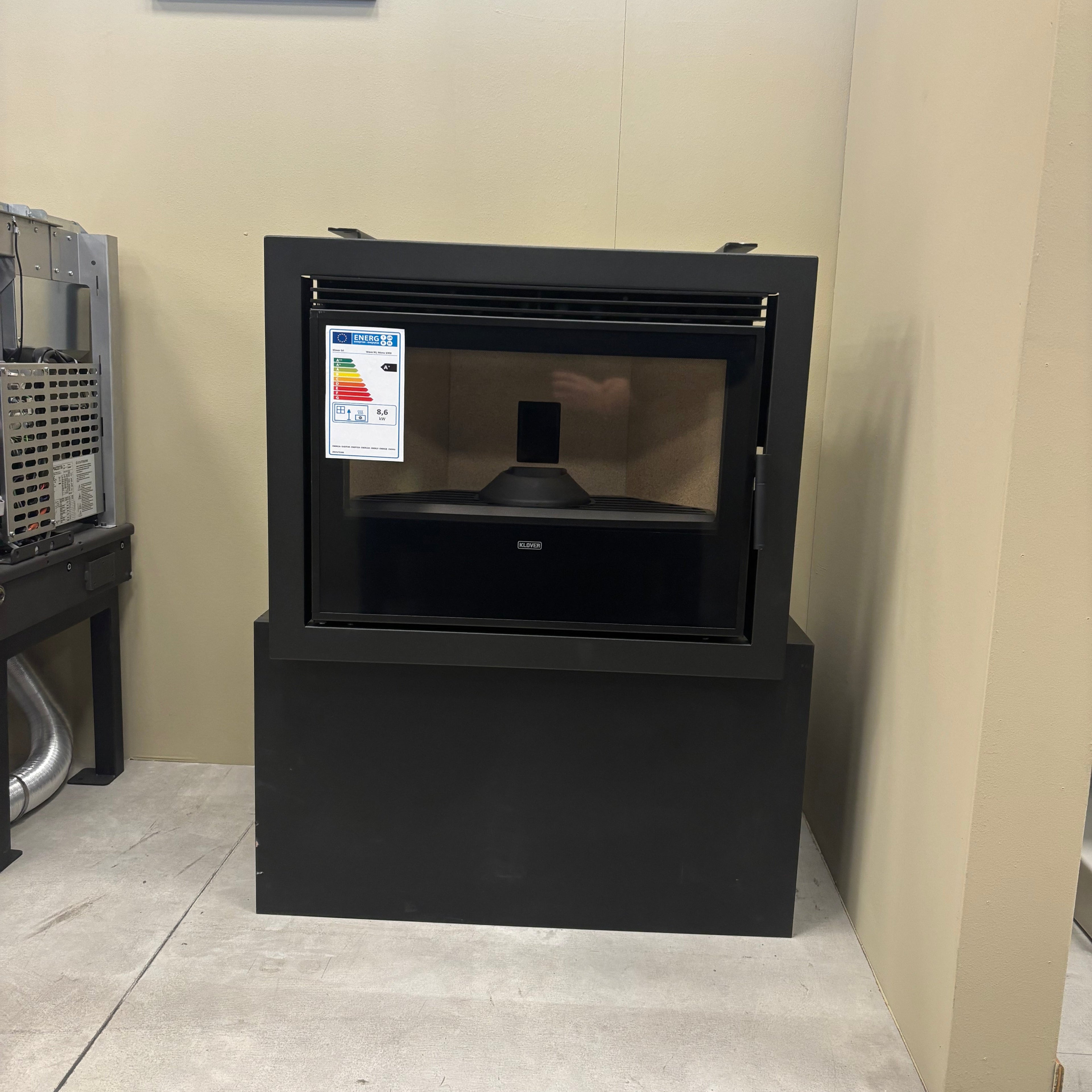 Caminetto a pellet Klover MONO 1000 con design moderno, visibile con porta e dettagli in acciaio, in ambiente domestico.