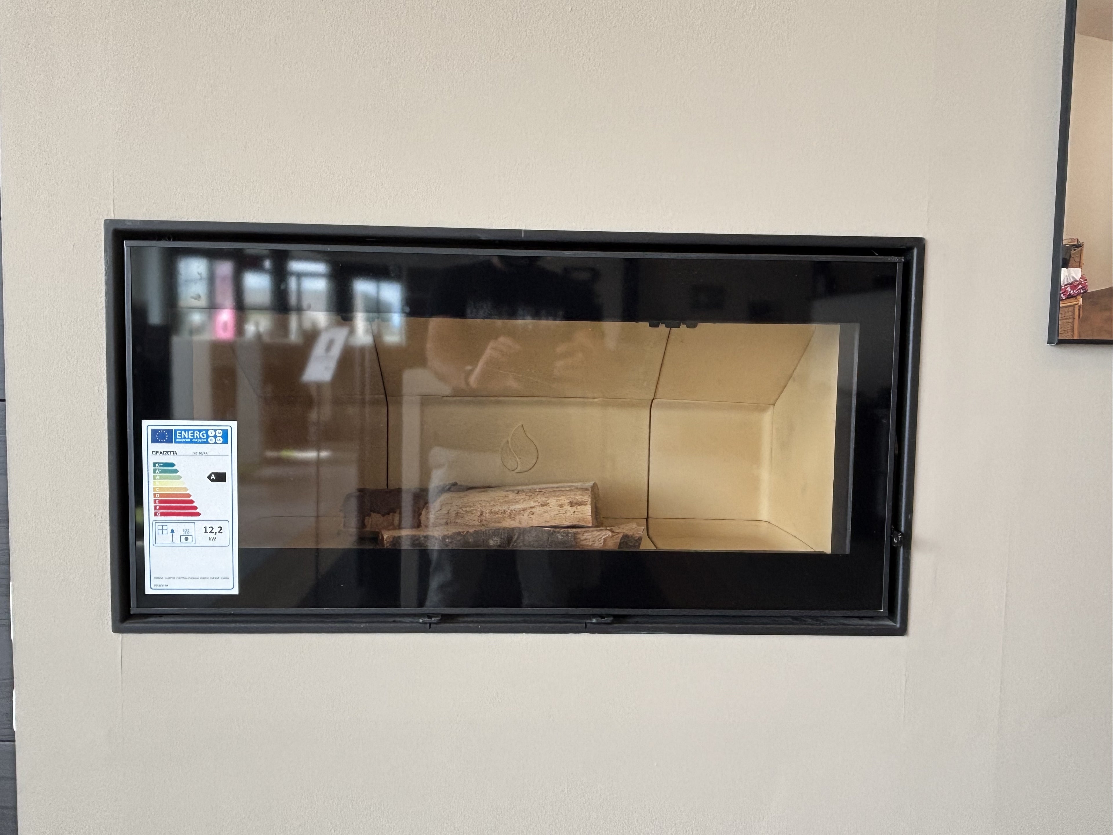 Caminetto a legna Piazzetta MC 90/44 con porta in vetro e rivestimento in pietra, ideale per riscaldare e arredare la casa.