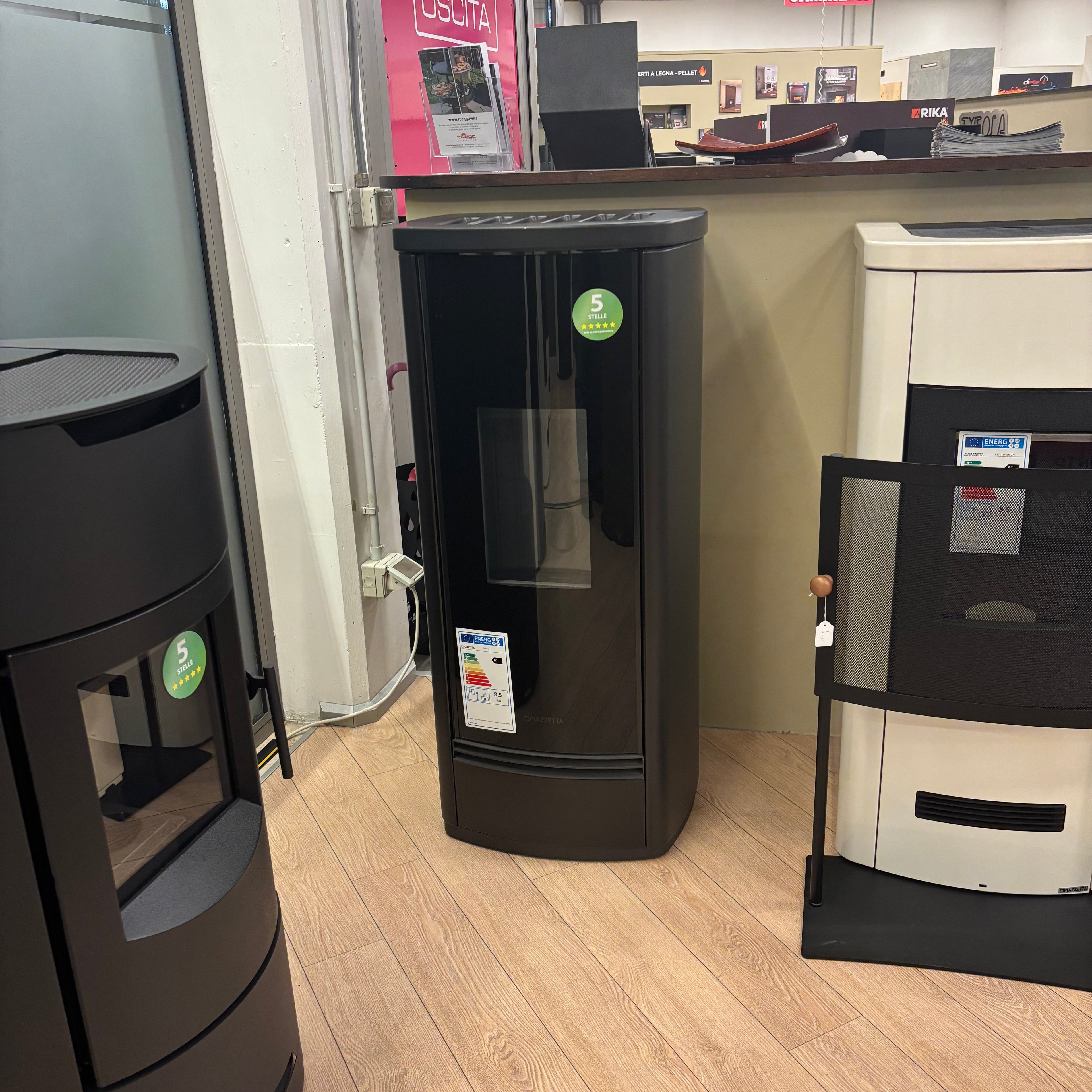 Stufa a pellet Piazzetta P220 M in stile modern, con superficie nera e portalegna, per riscaldamento domestico.