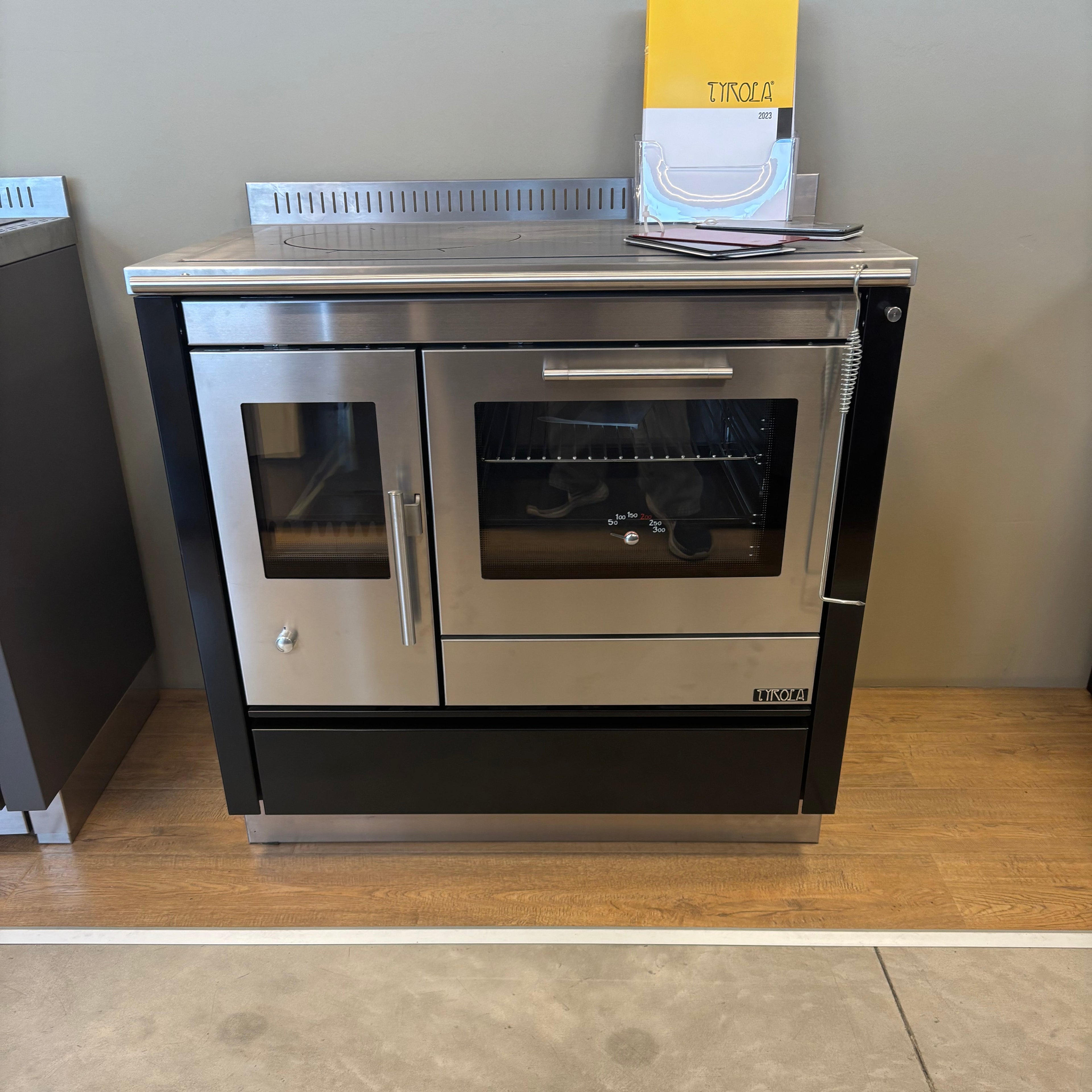 Stufa a legna Tyrola TR C 80 in acciaio nero con porta in vetro e maniglie robuste, ideale per riscaldare ambienti domestici.