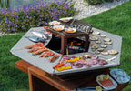 Barbecue a legna esagonale della Serie E di Vulcano Fire, in acciaio con superficie nera e manici in legno.